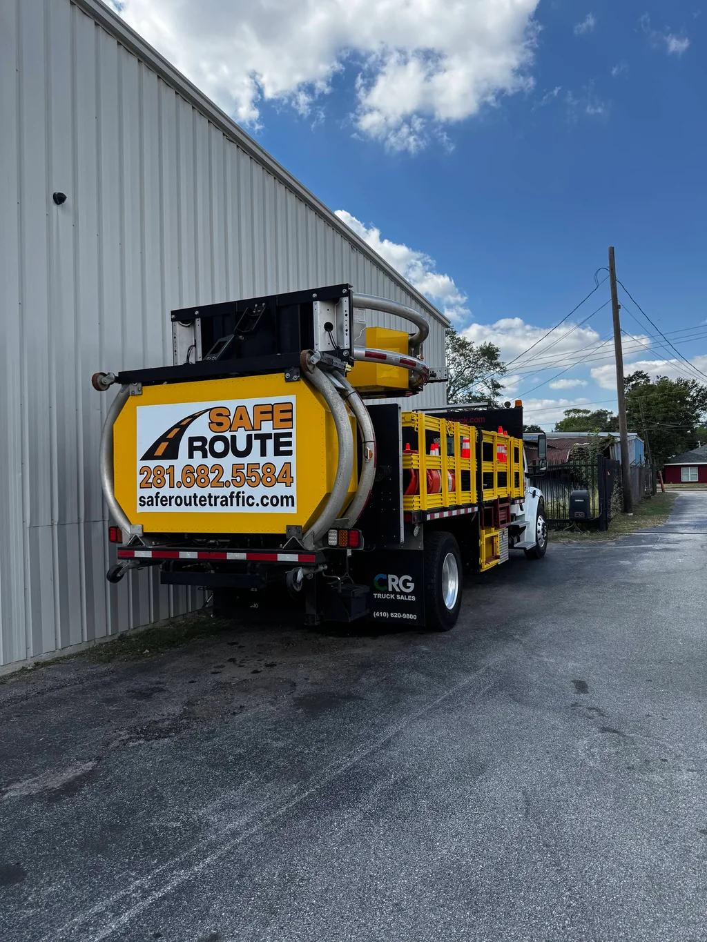 Rear of a Safe Route branded TMA truck parked beside a metal-sided building.