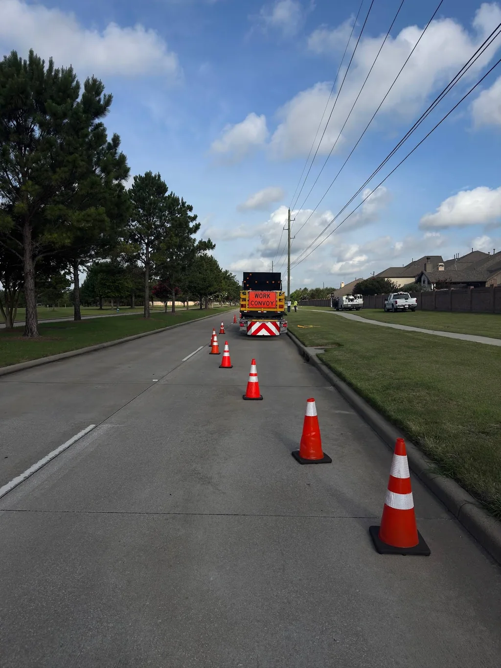 Cone taper leading toward a work-zone vehicle on a roadway.