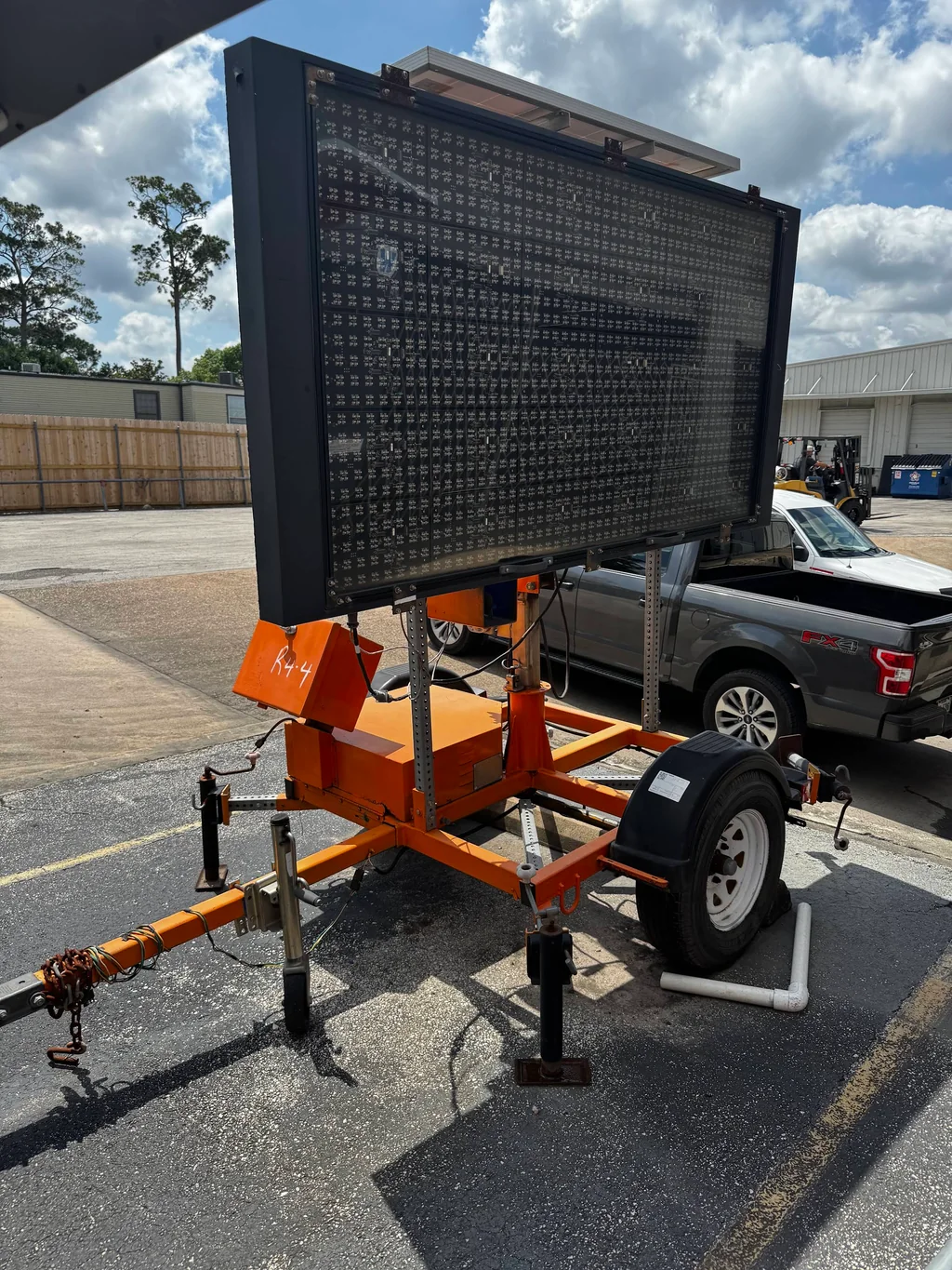 Trailer-mounted electronic message board parked beside a pickup truck.