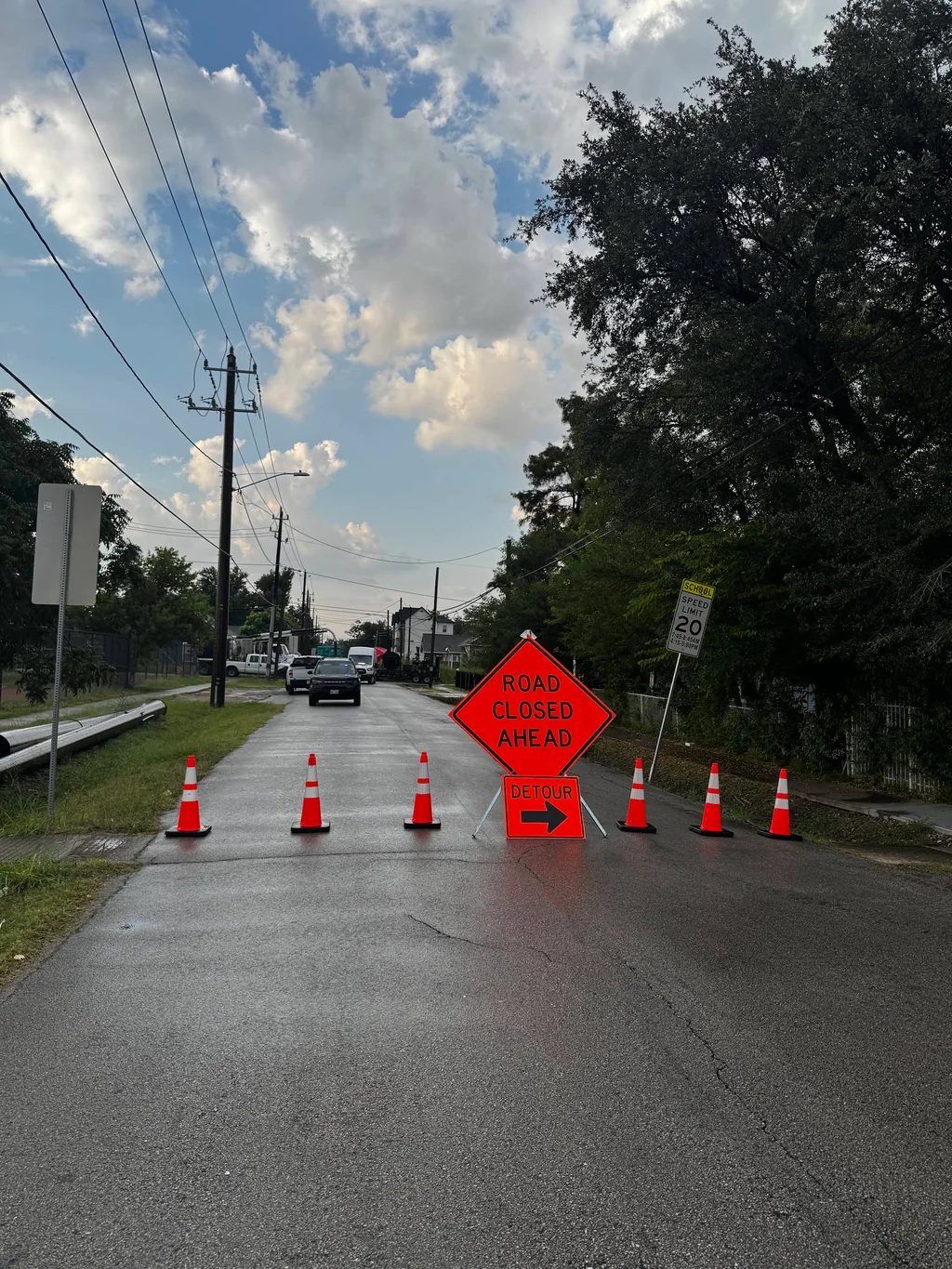 Road Closed Ahead sign and cones along a residential road.